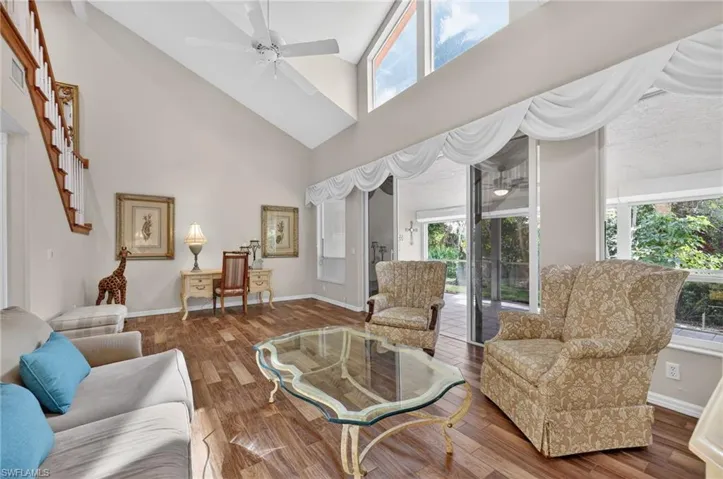 Living room featuring a ceiling fan, wood-look tile finished floors, and vaulted ceiling