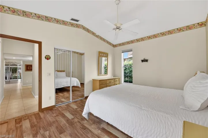 Bedroom with wood-look tile finished floors, a closet, lofted ceiling, and natural light