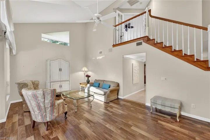 Living room featuring wood-look tile finished floors, vaulted ceiling, and ceiling fan