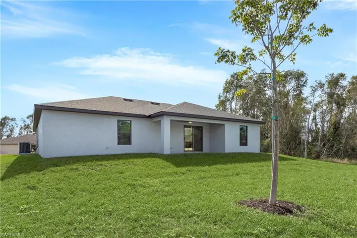Rear view of property with stucco siding, a yard, and a patio area
