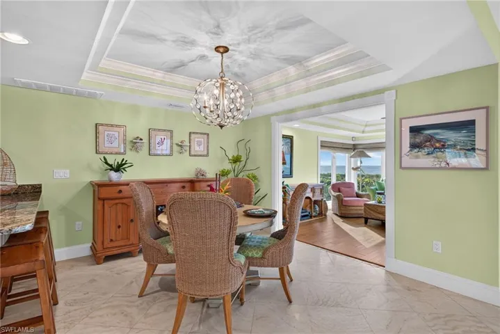 Tray ceiling featuring recessed lighting, a decorative sphere chandelier, stone-finish flooring, and crown molding