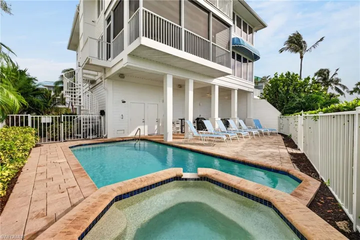 Multi-level exterior featuring a private swimming pool, integrated spa, covered patio area, and a white spiral staircase