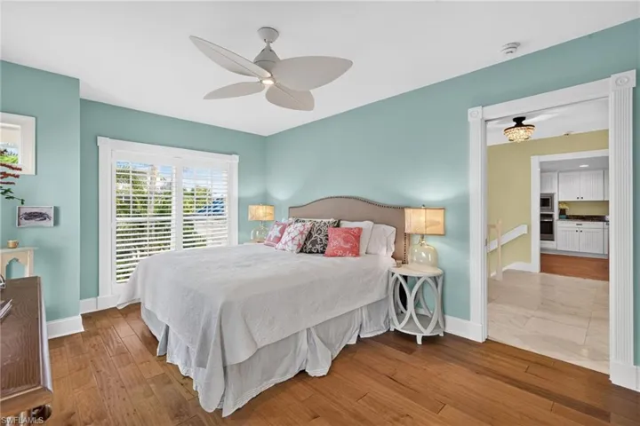 Wood-finish flooring, plantation shutters, custom millwork door casings, and a multi-blade ceiling fan