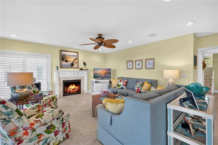 Living area featuring large-format tile flooring, recessed lighting, a ceiling fan, and a fireplace with a decorative mantel surround