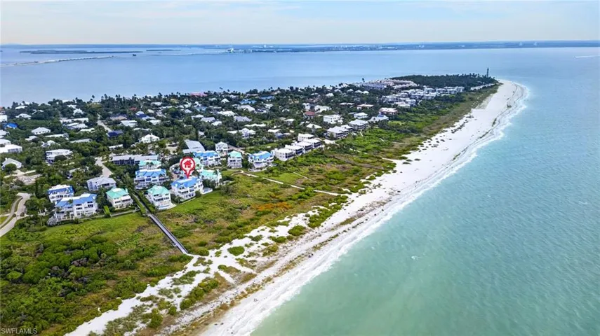 Aerial perspective of coastal property featuring direct beach access, expansive shoreline frontage, and native landscape vegetation