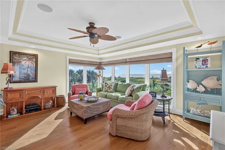 Tray ceiling with integrated recessed lighting, expansive wrap-around windows, and wood-finish flooring