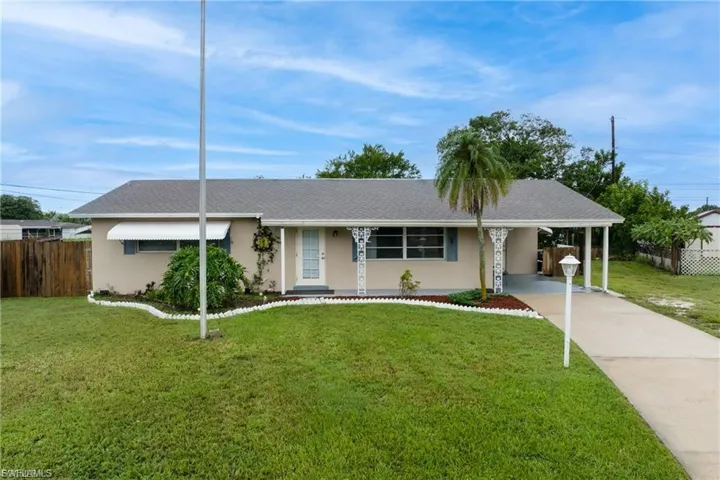 Single story home with a carport, concrete driveway, stucco siding, roof with shingles, and a porch