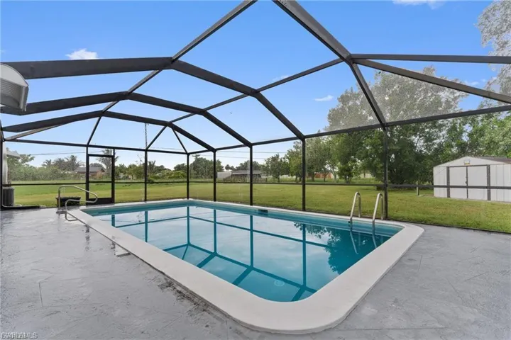 Swimming pool featuring a lawn, a sunroom, and a lanai