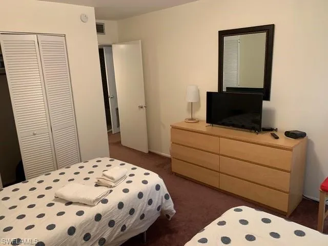 Bedroom featuring dark carpet and a closet