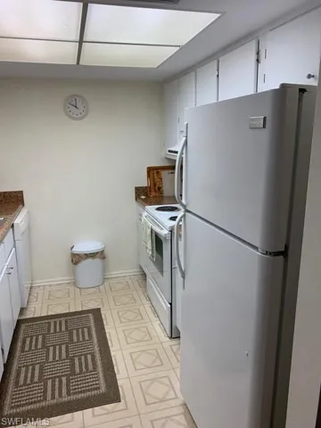 Kitchen featuring dishwasher, white electric stove, white cabinets, and refrigerator