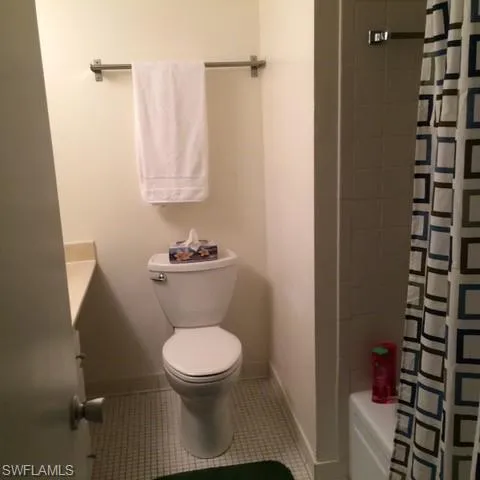 Bathroom featuring tile patterned floors, shower / bath combination with curtain, and toilet