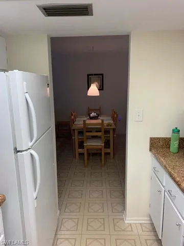 Kitchen with hanging light fixtures, fridge, and white cabinets