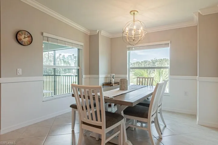 Dining space featuring a chandelier, plenty of natural light, crown molding, and light tile patterned floors