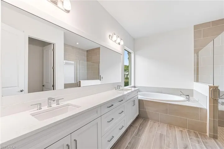 Bathroom with double vanity, a bath, a stall shower, and a sink