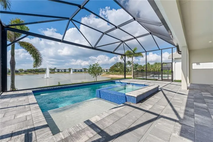 View of pool with a pool with connected hot tub, a lanai, a patio, and a water view