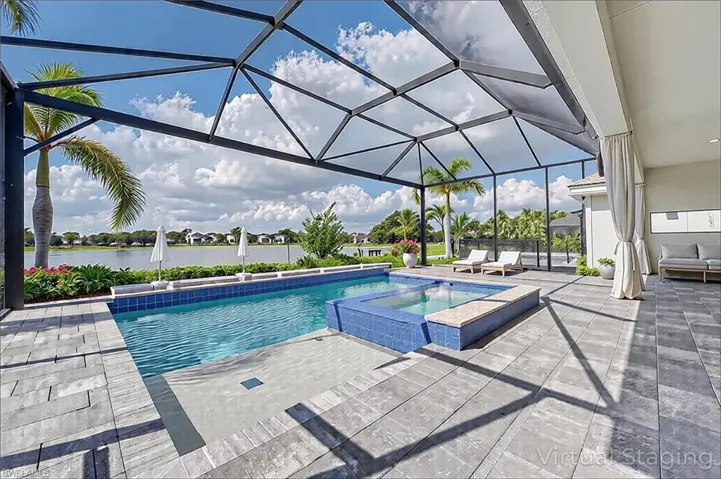 View of pool with a patio area, glass enclosure, a pool with connected hot tub, and a water view