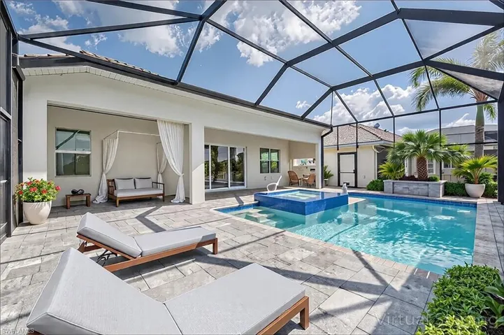 View of swimming pool with a lanai, a pool with connected hot tub, and a patio