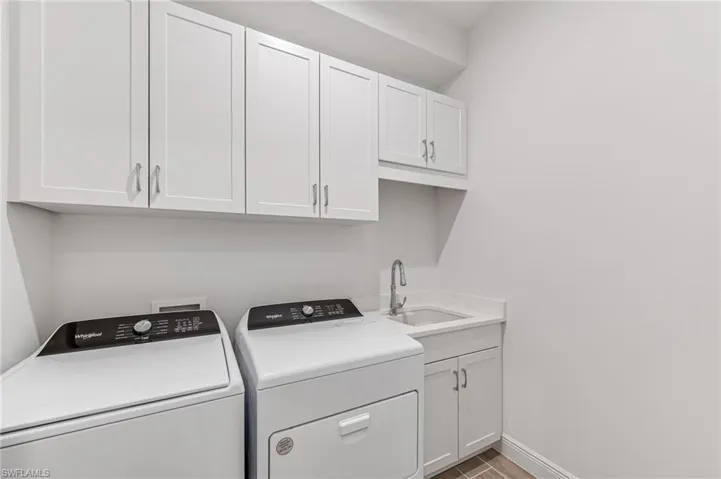 Washroom with washer and clothes dryer, wood finished floors, a sink, baseboards, and cabinet space