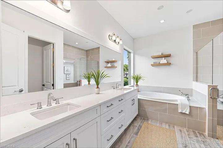 Bathroom with a bath, a sink, double vanity, and a stall shower
