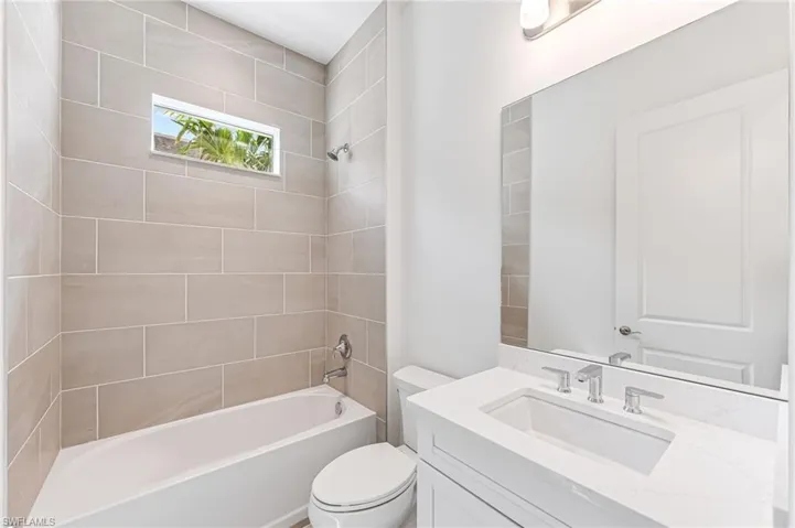 Bathroom featuring shower / bath combination, toilet, and vanity