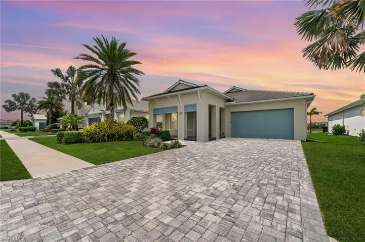 View of front of home with an attached garage, a lawn, stucco siding, and driveway