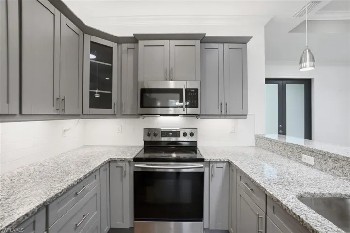 Light & bright tchen includes contemporary gray cabinetry, granite counters & stainless-steel appliances.