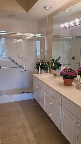 Full bathroom with tile patterned floors, vanity, and a stall shower