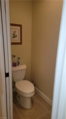 Bathroom featuring toilet, baseboards, and tile patterned flooring