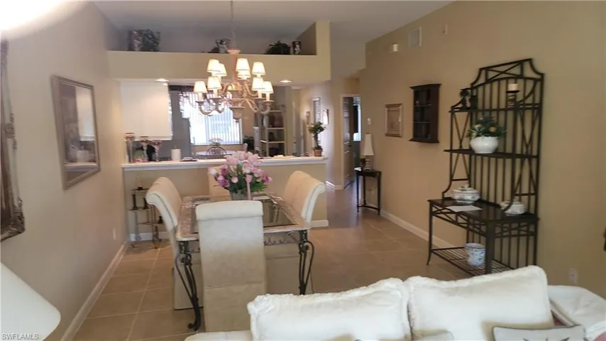 Dining room with tile patterned flooring, a notable chandelier, and baseboards