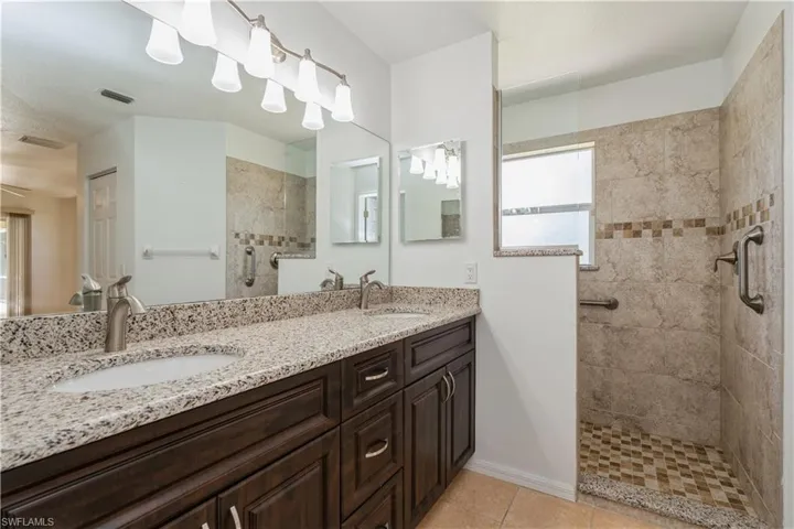 Owner's bath featuring a shower with door, dual sinks, and oversized vanity