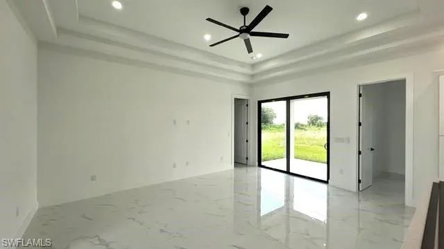 Unfurnished room featuring light tile patterned flooring, ceiling fan, and a raised ceiling