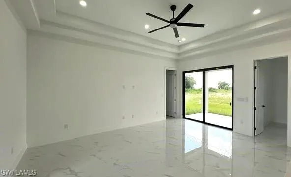 Spare room with a raised ceiling, light tile patterned floors, and ceiling fan