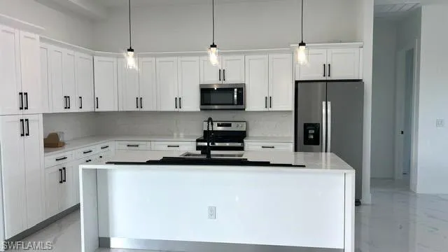 Kitchen featuring white cabinets, an island with sink, and stainless steel appliances