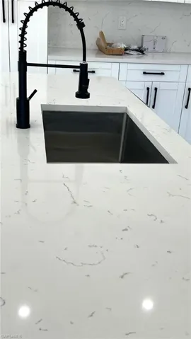 Room details with white cabinetry and sink