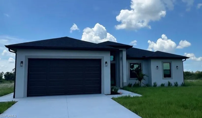Single story home with a garage and a front lawn