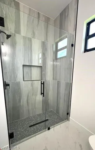 Bathroom featuring tile patterned floors, a shower with door, and toilet