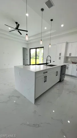 Kitchen featuring light tile patterned flooring, white cabinetry, ceiling fan, pendant lighting, and sink