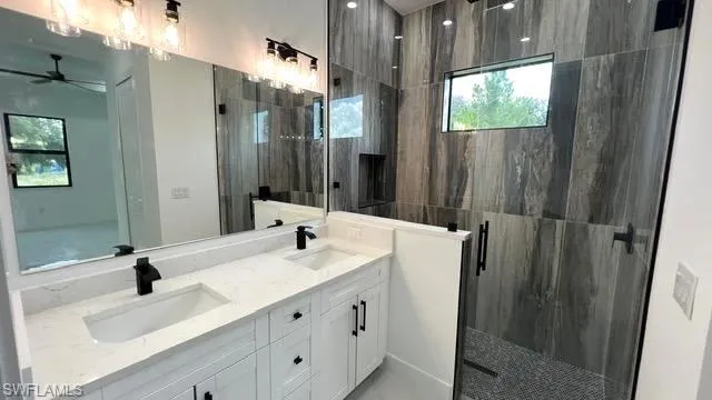 Bathroom with an enclosed shower, ceiling fan, and dual bowl vanity