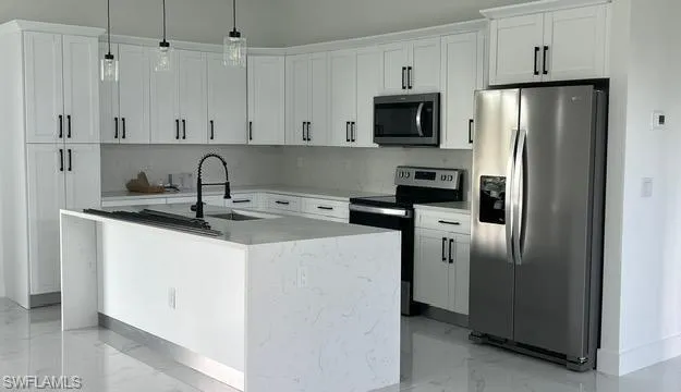 Kitchen featuring sink, white cabinetry, a center island with sink, and stainless steel appliances