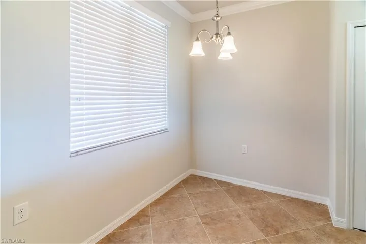 Unfurnished room with ornamental molding, light tile patterned floors, and a chandelier