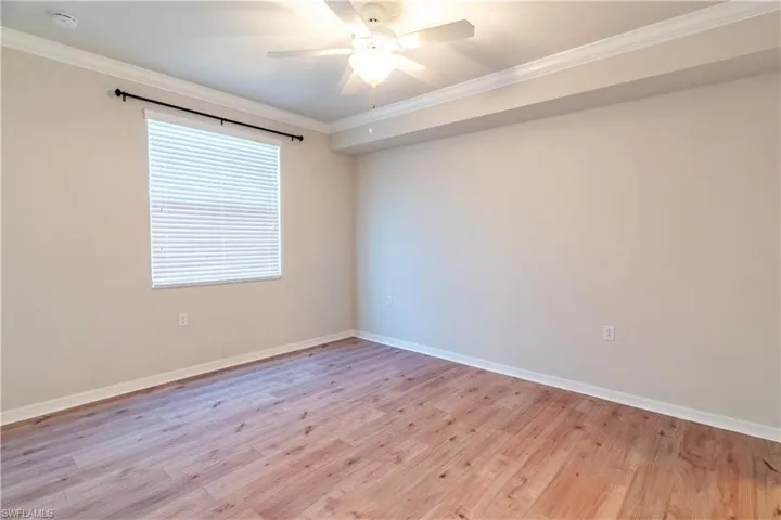 Empty room featuring ornamental molding, light wood finished floors, ceiling fan, and a smoke detector