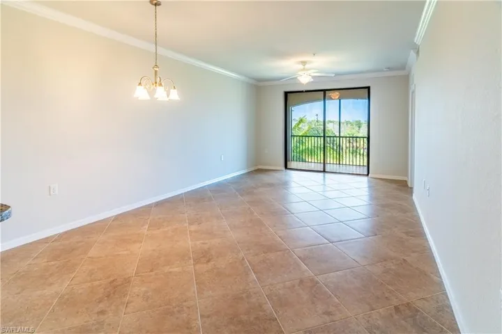 Empty room featuring ornamental molding, light tile patterned floors, a ceiling fan, and a chandelier