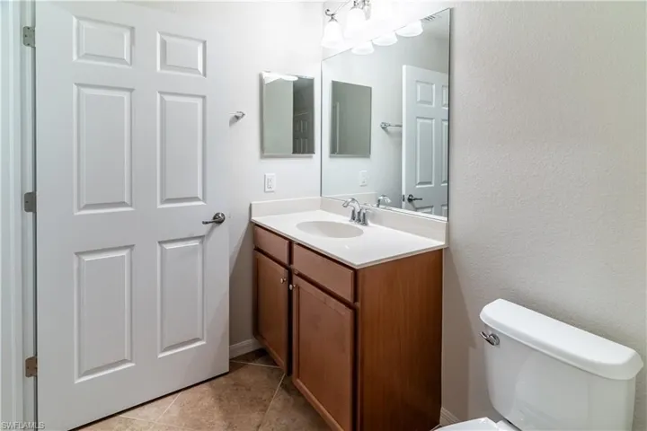 Half bath with vanity, light tile patterned floors, and a textured wall