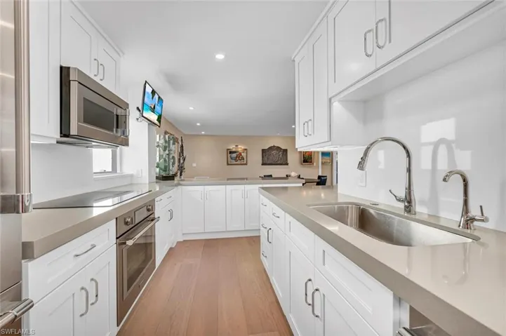 Kitchen with light countertops, light wood-style flooring, white cabinets, appliances with stainless steel finishes, and a sink
