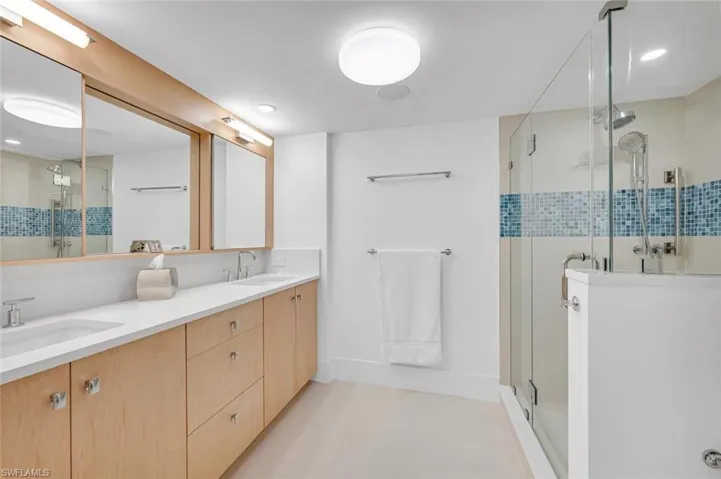 Bathroom featuring a stall shower, double vanity, and a sink