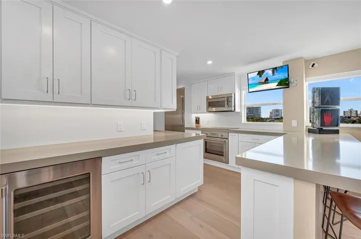 Kitchen featuring appliances with stainless steel finishes, white cabinets, plenty of natural light, and beverage cooler