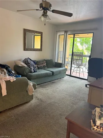 Carpeted living room with ceiling fan and a textured ceiling