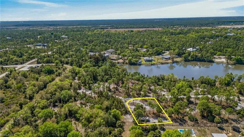 Aerial view of property and surrounding area with property parcel outlined and a large body of water