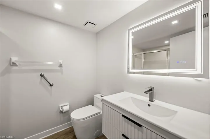 Full bathroom with vanity, recessed lighting, dark wood-style floors, and an enclosed shower