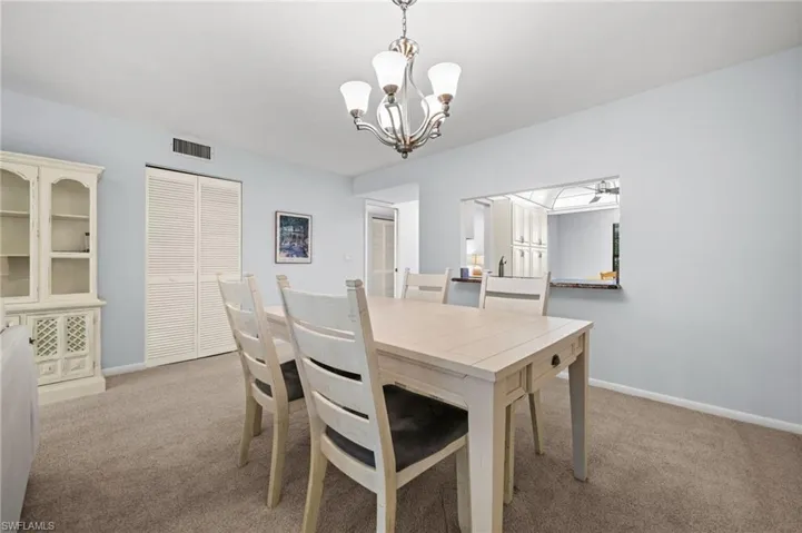Carpeted dining room with suspended lighting and baseboards